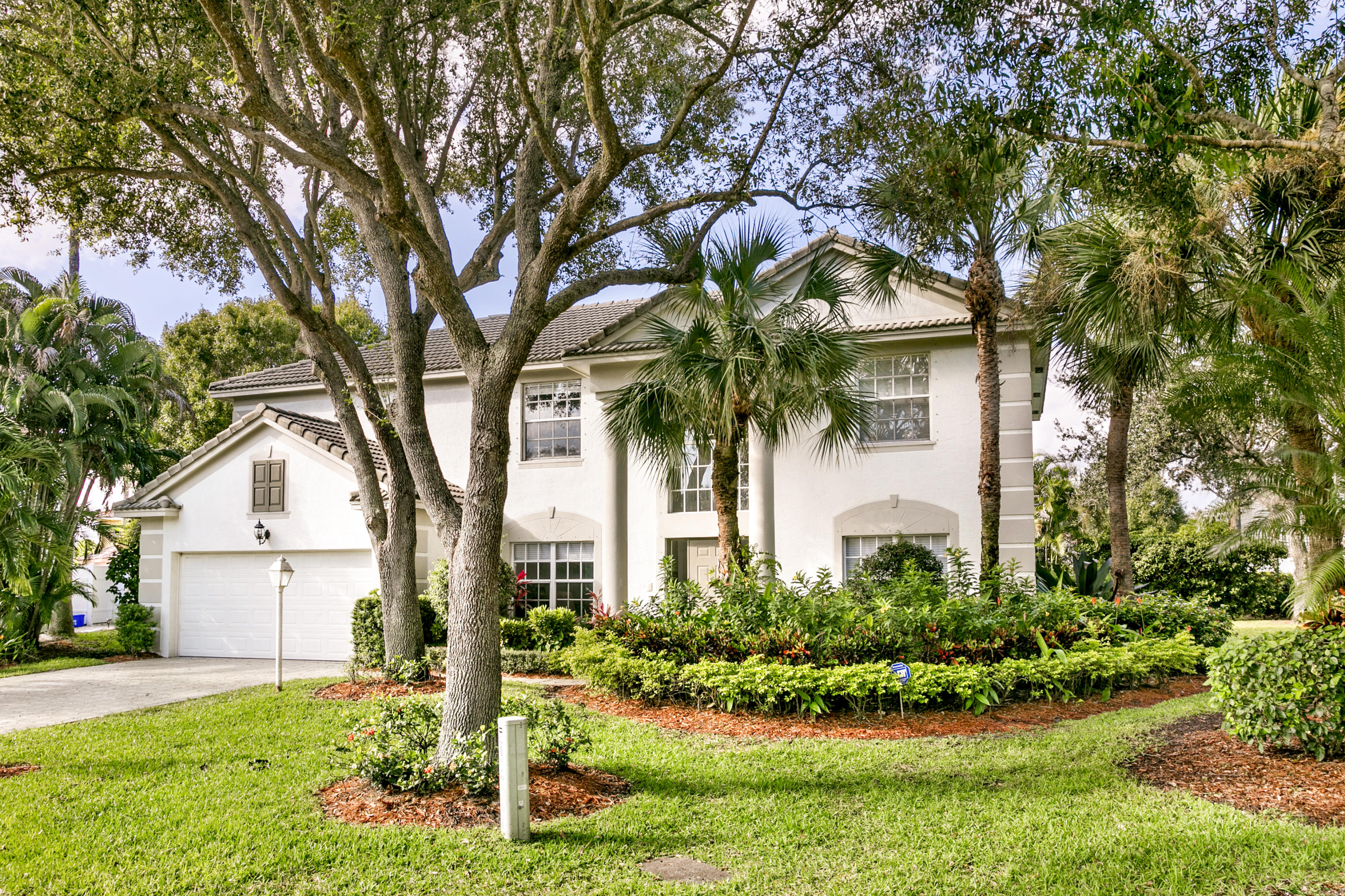 a front view of a house with a garden and trees