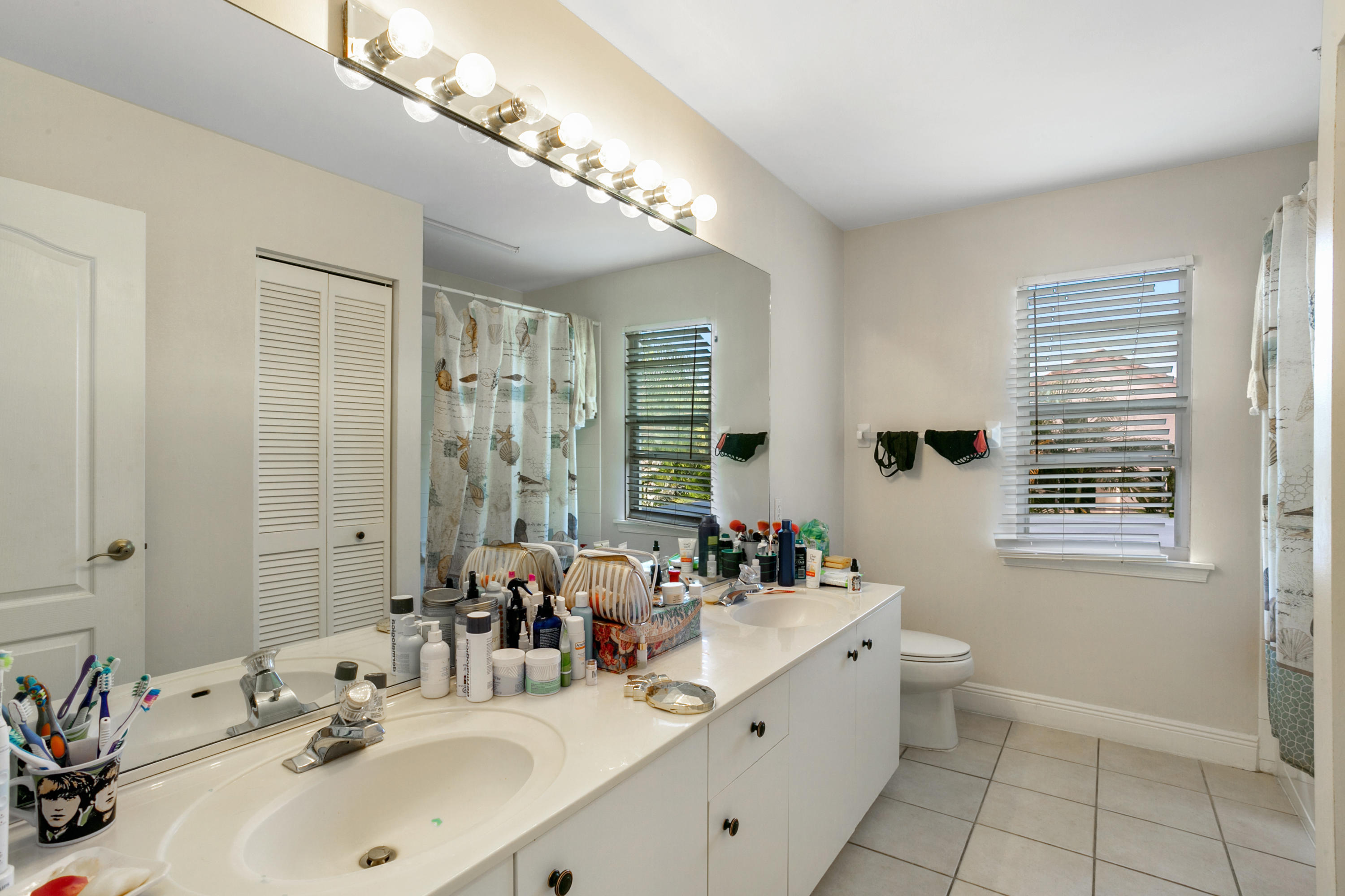 204 Seagull Point Jupiter, FL 33458 - Photo 12 of 18 a bathroom with a double vanity sink a large mirror and a shower