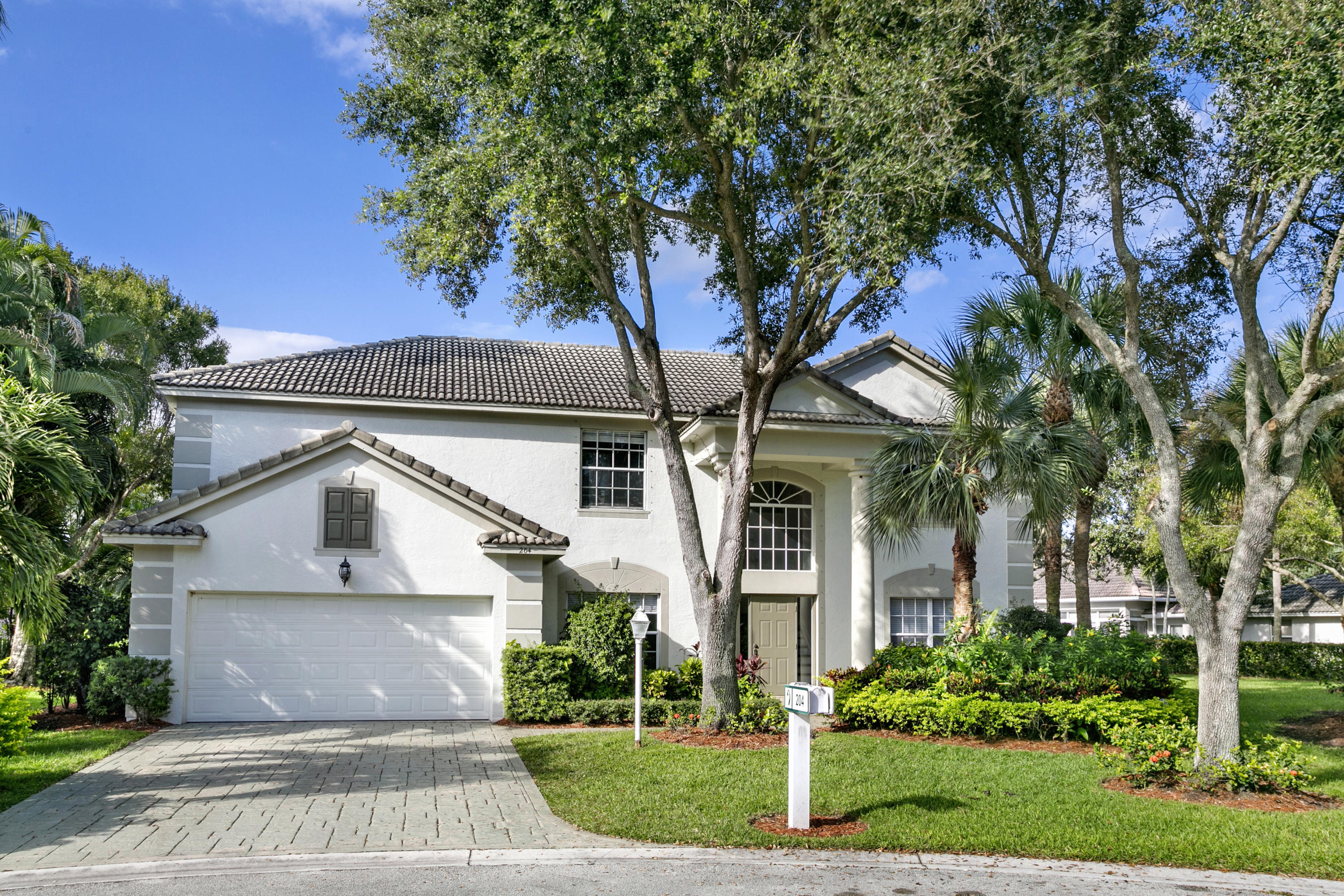 204 Seagull Point Jupiter, FL 33458 - Photo 2 of 18 a view of a white house next to a yard with plants and trees