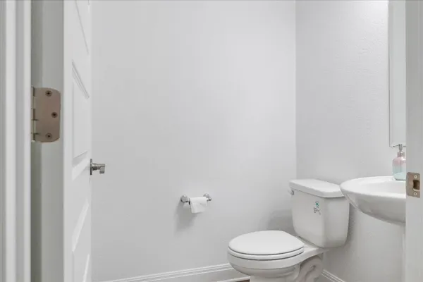 a white toilet sitting next to a white sink and vanity