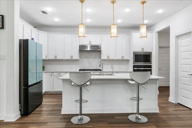 a kitchen with stainless steel appliances granite countertop a sink a refrigerator and a stove