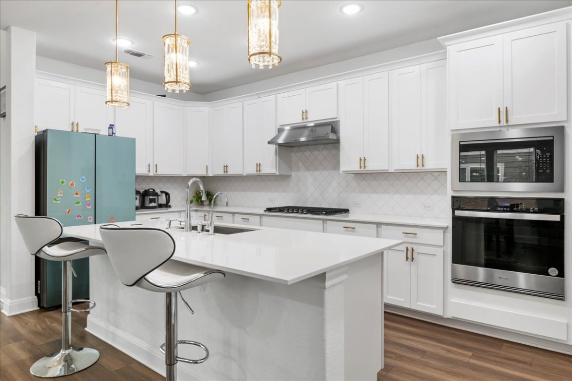 240 Inlet Lane Leander, TX 78641 - Photo 7 of 33 a kitchen with stainless steel appliances granite countertop a stove top oven a refrigerator a sink and a dining table with wooden floor