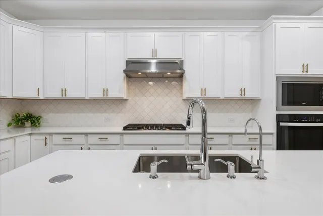 a kitchen with kitchen island a sink a stove and cabinets