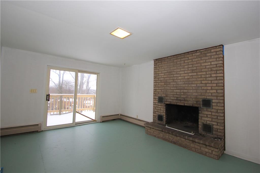 1122 Hamil Road Penn Hills, PA 15147 - Photo 8 of 24 Family Room - The family room is on the other side of the kitchen and it has a sliding door to the new rear deck. The log burning fireplace has a floor to ceiling brick hearth ready to warm you up on those cold winter nights!