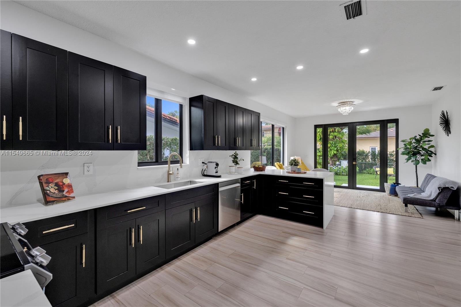 1543 Bird Road Coral Gables, FL 33146 - Photo 21 of 65 a large kitchen with stainless steel appliances granite countertop a sink dishwasher stove and wooden cabinets with wooden floor
