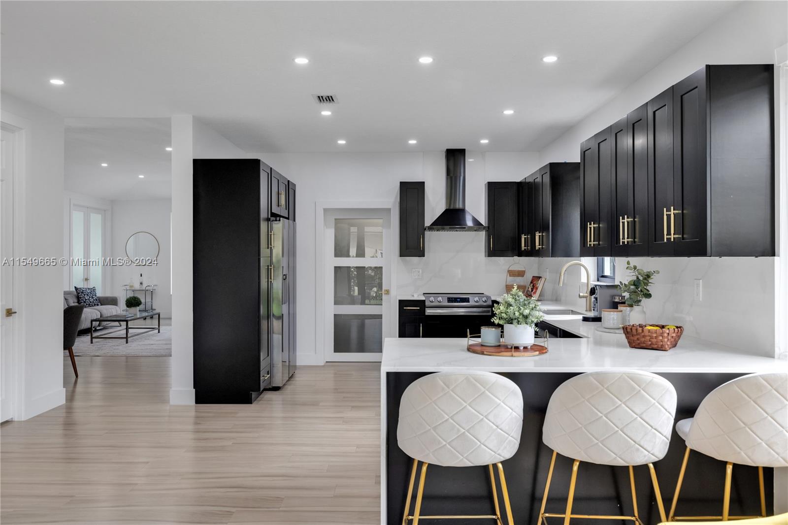 1543 Bird Road Coral Gables, FL 33146 - Photo 23 of 65 a kitchen with stainless steel appliances kitchen island granite countertop a refrigerator a stove a sink a dining table and chairs with wooden floor
