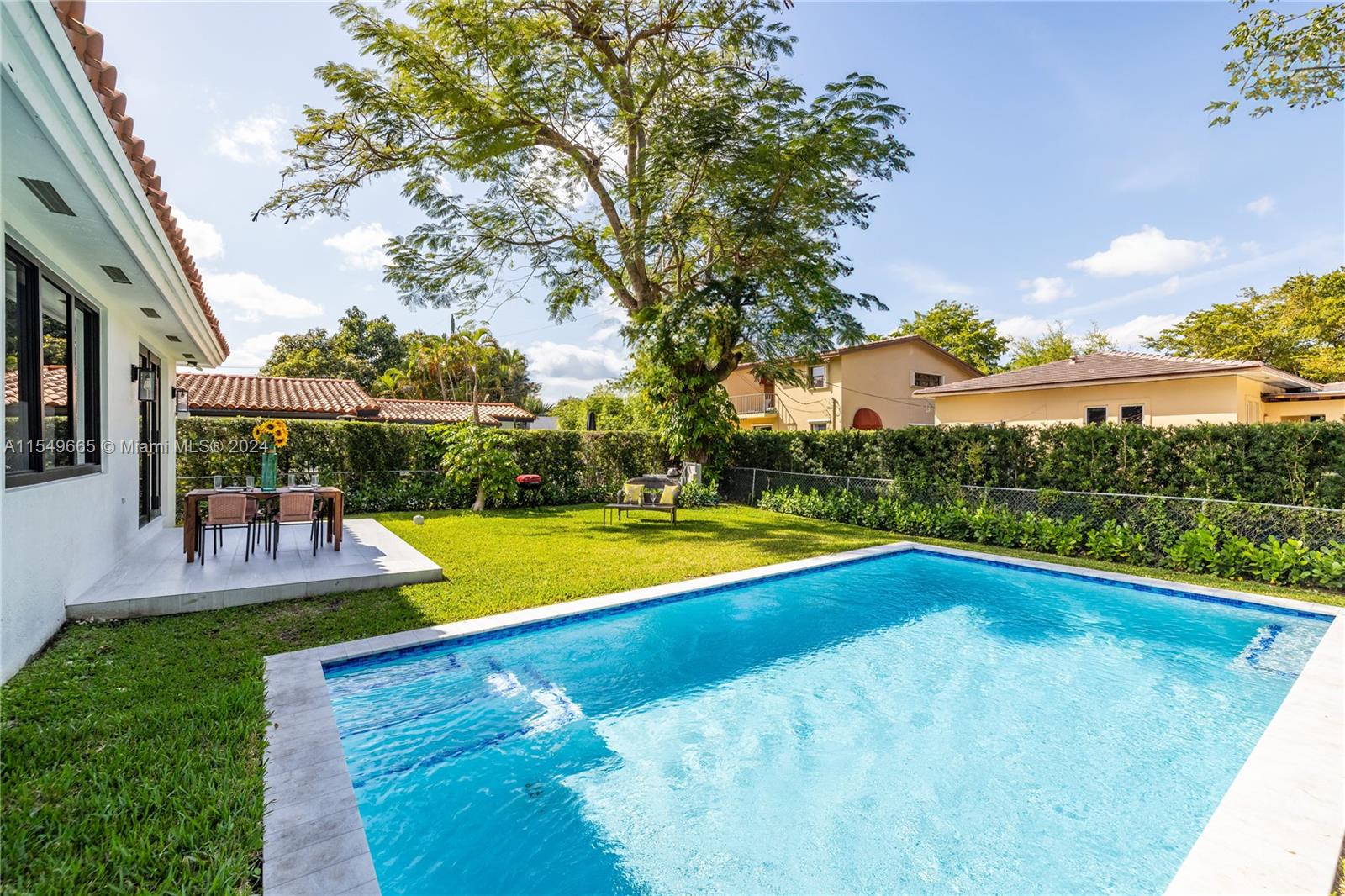 1543 Bird Road Coral Gables, FL 33146 - Photo 45 of 65 a view of a swimming pool with lawn chairs and a big yard