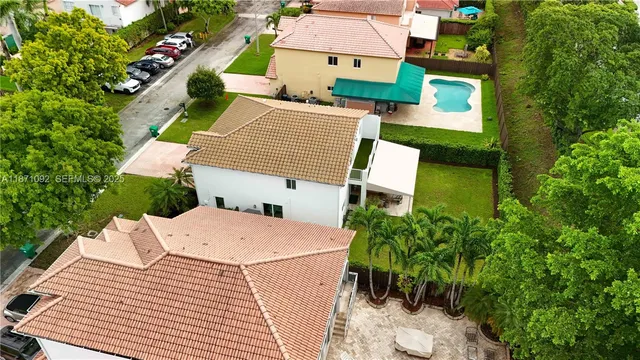 an aerial view of a house with a yard and trees all around