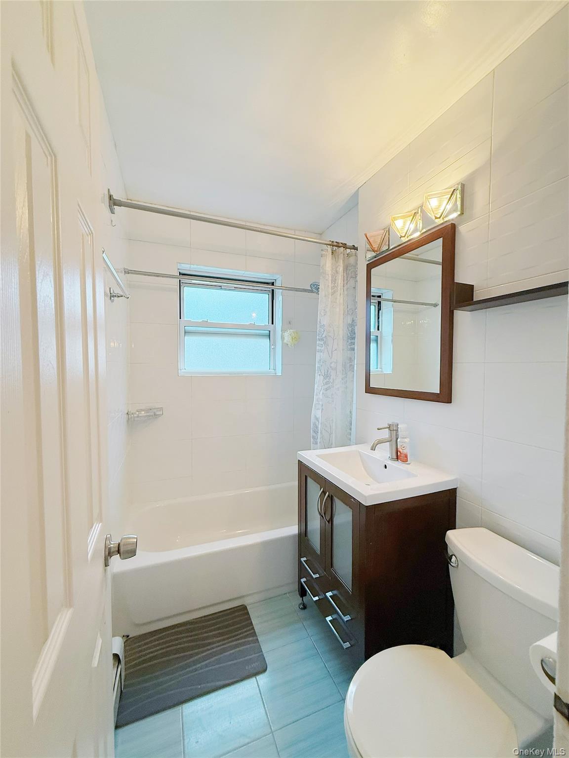 152-44 Jewel Avenue, Unit 102A Queens, NY 11367 - Photo 9 of 12 a bathroom with a toilet a sink and mirror