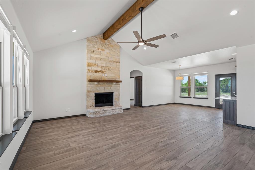5470 Compass Way Bluff Dale, TX 76433 - Photo 9 of 26 an empty room with windows fireplace and wooden floor