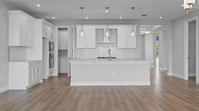 a large white kitchen with kitchen island a sink a refrigerator and white cabinets