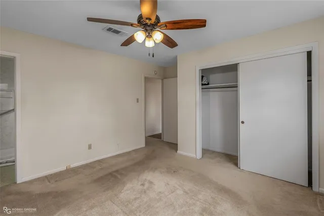 an empty room with a chandelier fan and windows