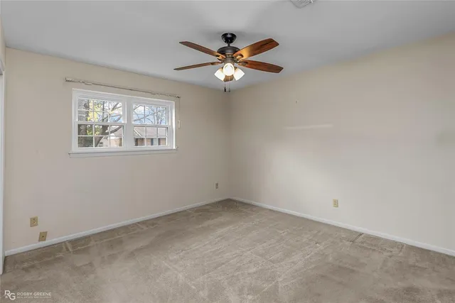 an empty room with a chandelier fan and windows