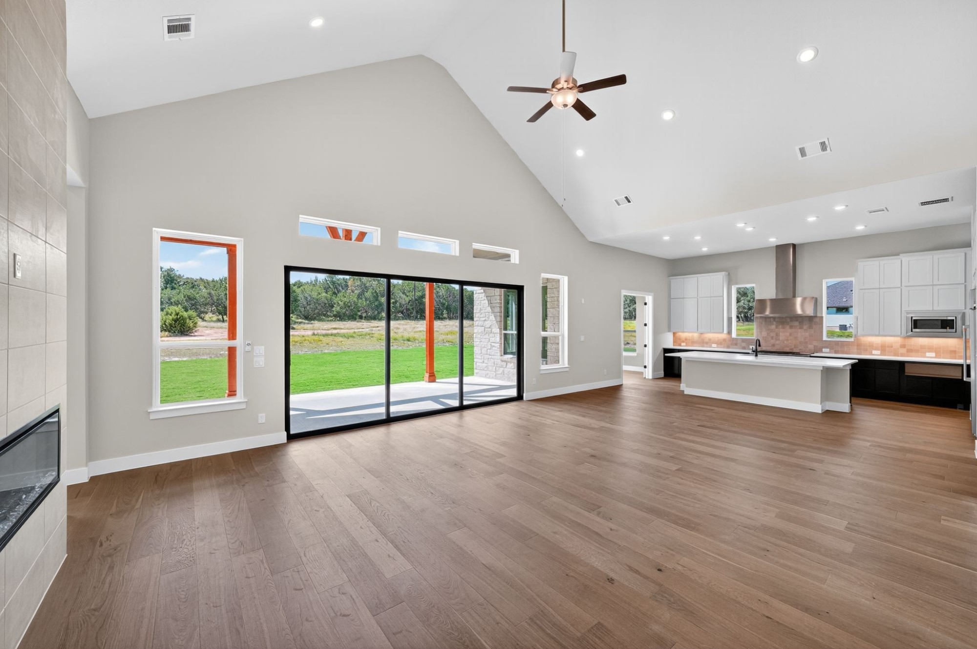 205 Three Rivers Road Georgetown, TX 78633 - Photo 4 of 32 Unfurnished living room featuring high vaulted ceiling, a tiled fireplace, light wood-type flooring, recessed lighting, and a ceiling fan