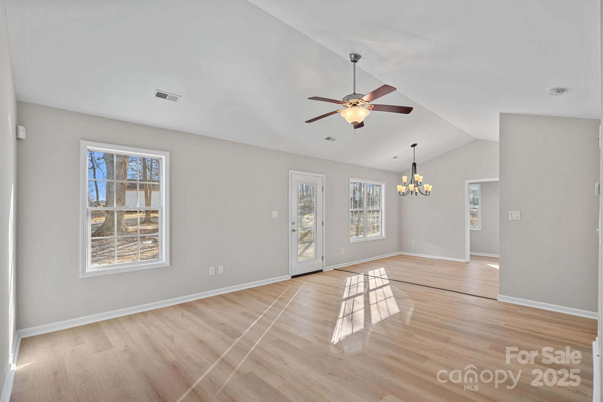 7100 Windsong Way Wingate, NC 28174 - Photo 4 of 26 an empty room with wooden floor chandelier fan and windows