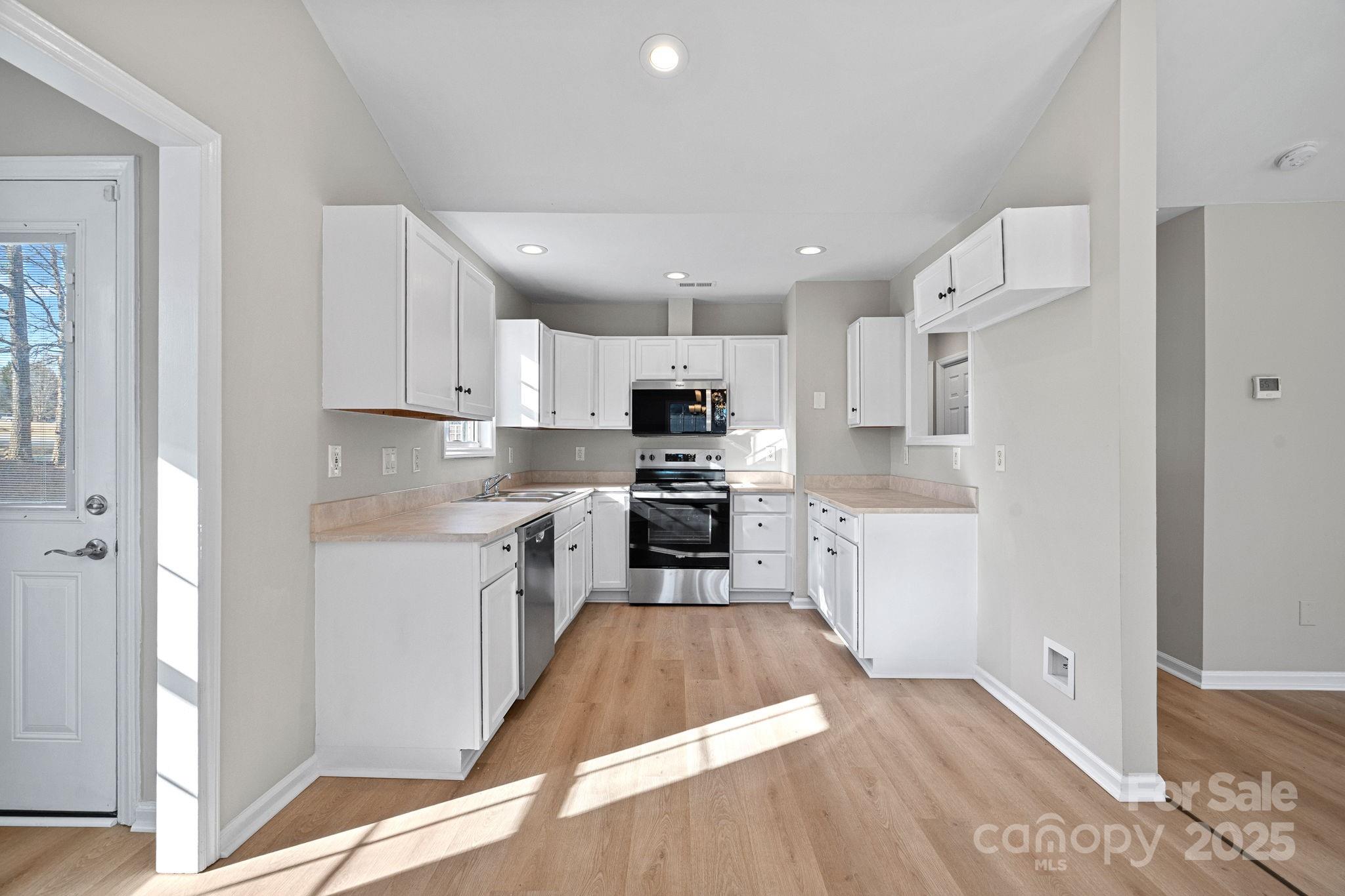 7100 Windsong Way Wingate, NC 28174 - Photo 9 of 26 a kitchen with granite countertop a refrigerator a sink dishwasher and a stove with wooden floor