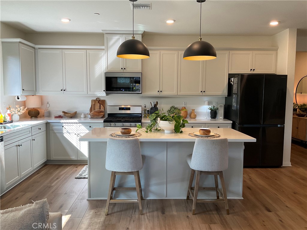 30153 Cyn Rnch Drive Homeland, CA 92548 - Photo 3 of 19 a kitchen with stainless steel appliances a dining table chairs refrigerator and microwave