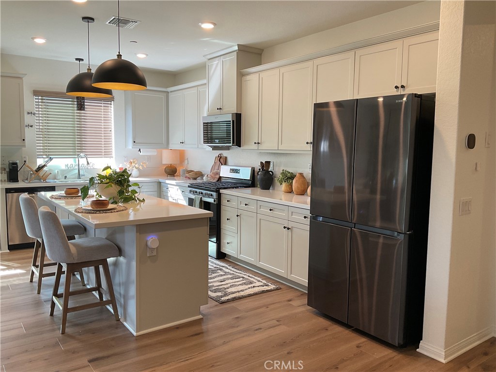 30153 Cyn Rnch Drive Homeland, CA 92548 - Photo 4 of 19 a kitchen with stainless steel appliances kitchen island granite countertop a refrigerator a sink a stove a dining table and chairs