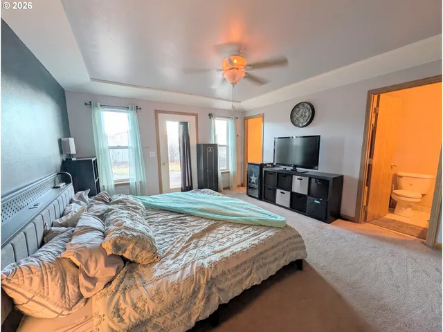 a spacious bedroom with a bed and a flat tv screen on dresser