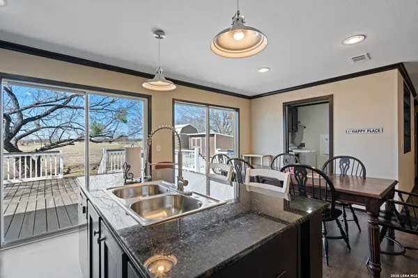 a kitchen island with stainless steel appliances granite countertop a sink a stove and a wooden cabinets