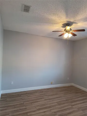 a view of a room with wooden floor and a chandelier fan