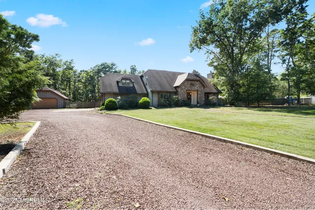 a view of a house with a yard and large trees