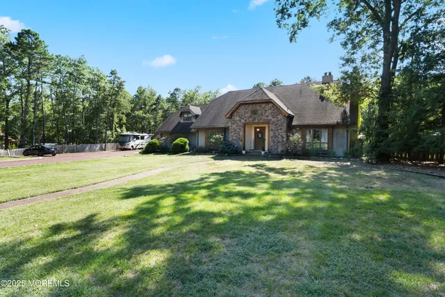 a view of a house with a big yard and large trees