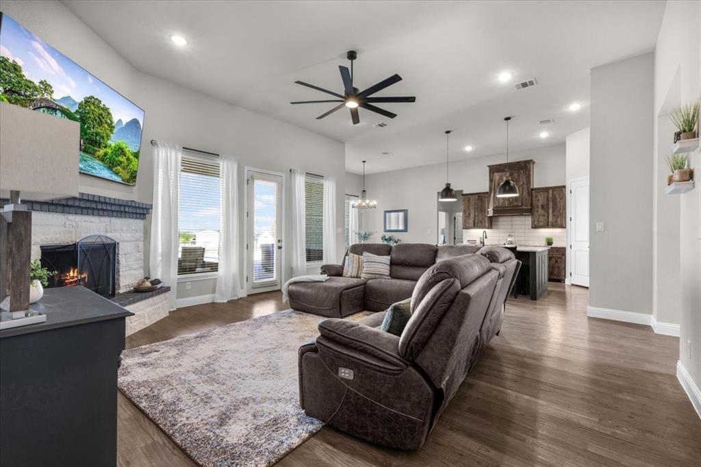 329 Palo Alto Drive Springtown, TX 76082 - Photo 5 of 34 Spacious open-concept living room featuring high ceilings, a stone fireplace, abundant natural light, and seamless flow into the kitchen.
