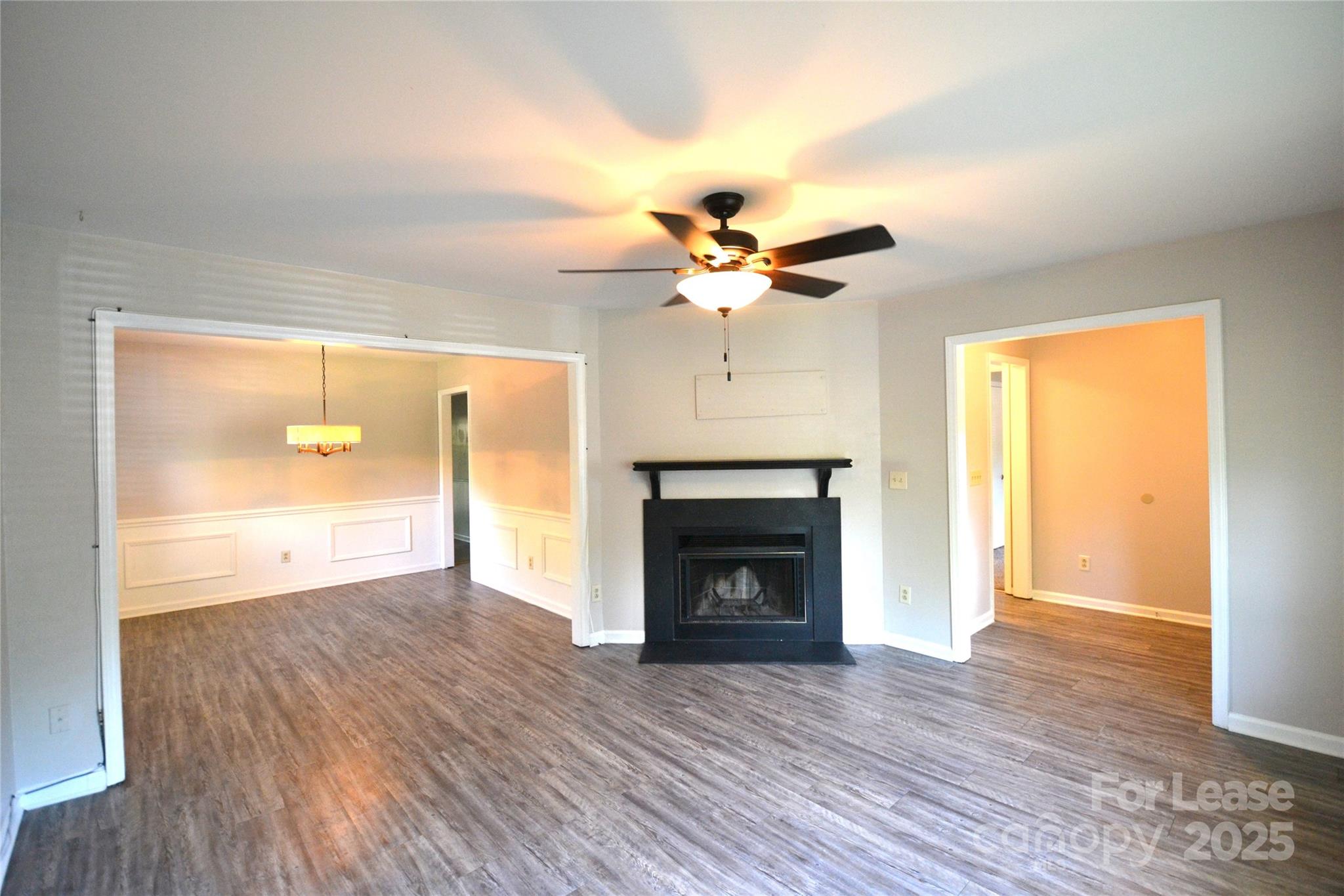 8317 Summer Glen Circle Charlotte, NC 28227 - Photo 5 of 30 an empty room with wooden floor a ceiling fan and a fireplace