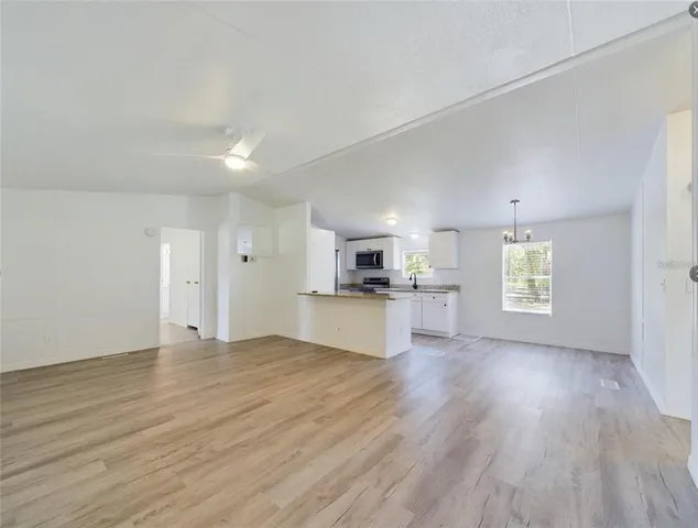 an empty room with wooden floor and a kitchen