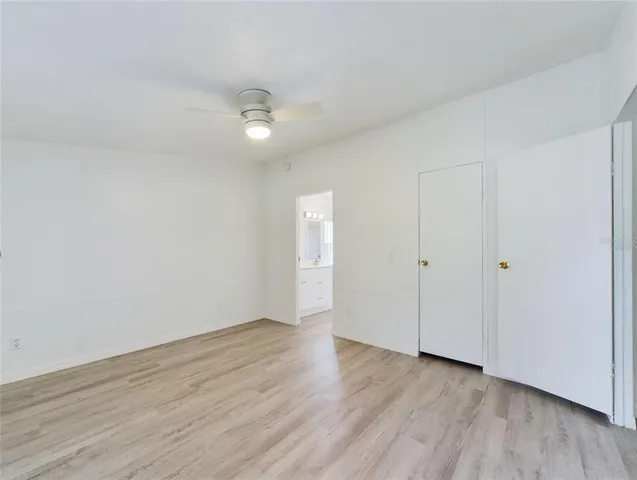 an empty room with wooden floor and ceiling fan