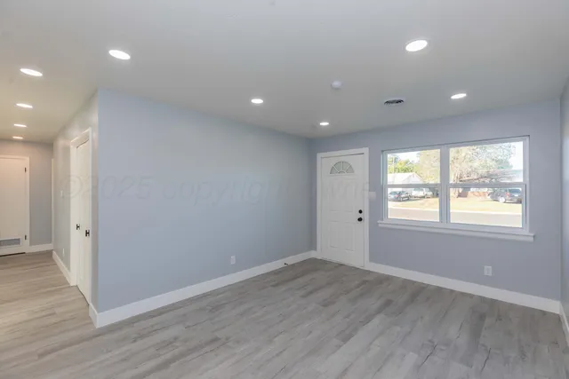 an empty room with wooden floor and windows