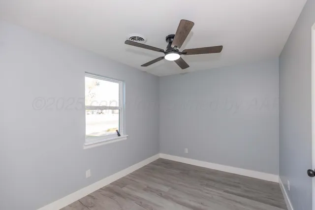 an empty room with wooden floor fan and windows