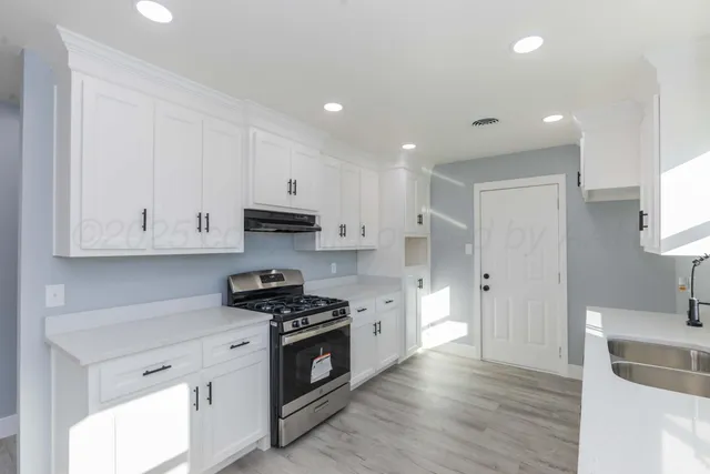a kitchen with granite countertop a sink a stove and cabinets