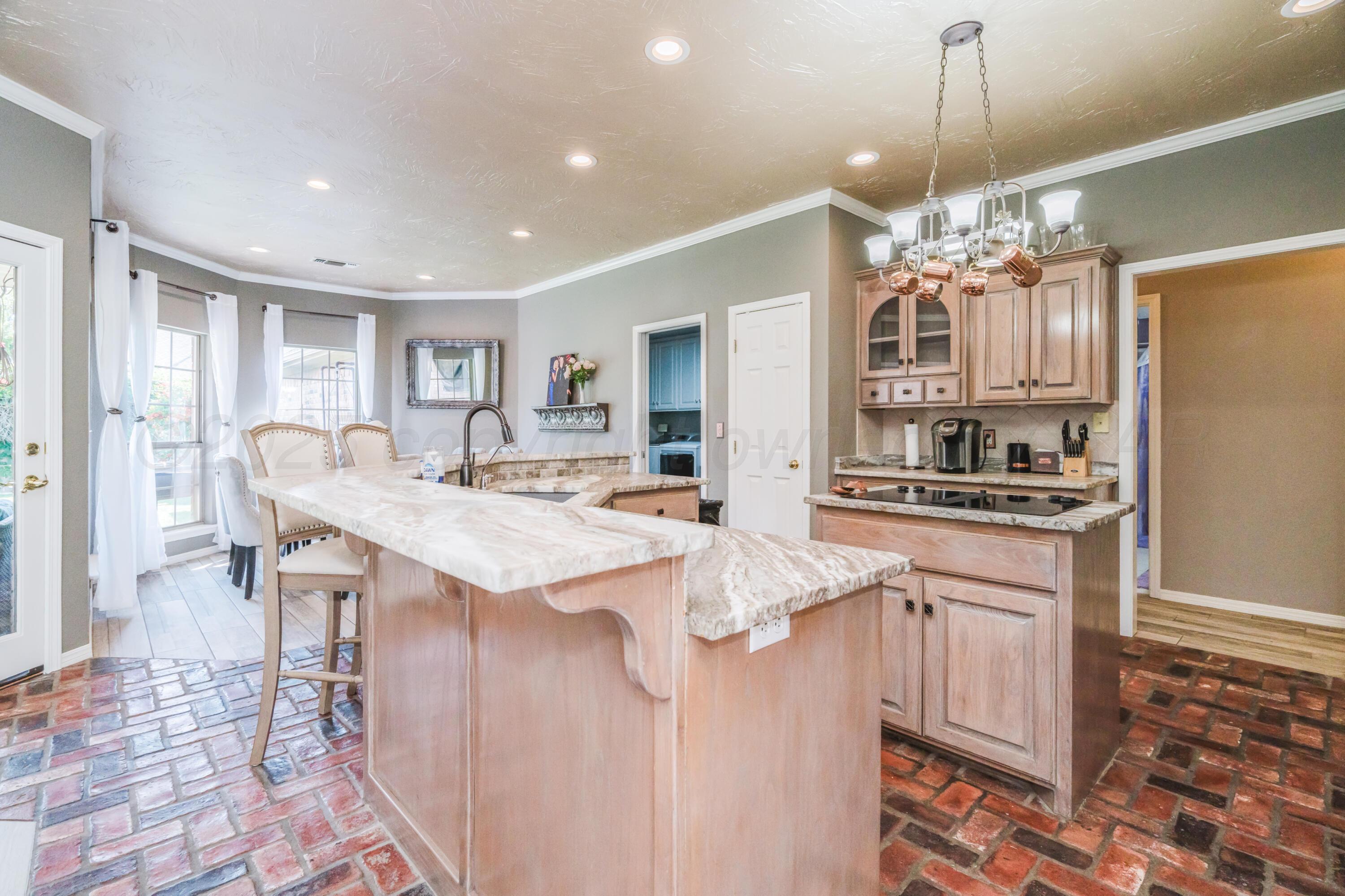 8216 Progress Drive Amarillo, TX 79119 - Photo 12 of 58 a large kitchen with kitchen island a sink stove a refrigerator and white cabinets with wooden floor