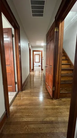 a view of a hallway with wooden floor and stairs