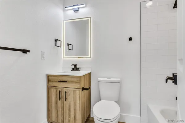 a bathroom with a toilet a sink a mirror and vanity