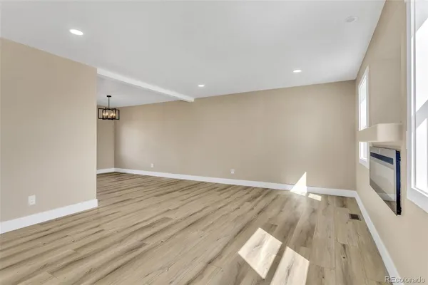 an empty room with wooden floor and a ceiling fan