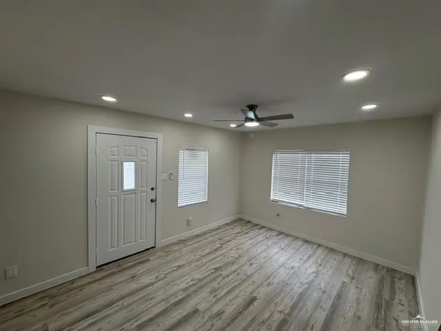 an empty room with wooden floor chandelier and windows