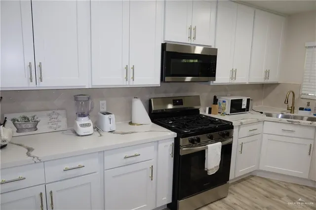 a kitchen with stainless steel appliances granite countertop white cabinets and a stove a oven with white countertops