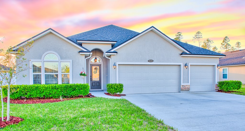 95199 Windflower Trail Fernandina Beach, FL 32034 - Photo 1 of 29 a front view of a house with a yard and garage