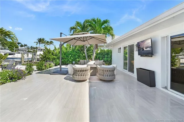 a view of a patio with table and chairs under an umbrella with potted plants