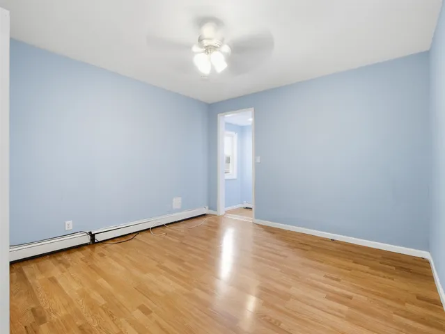 a view of an empty room with window and wooden floor