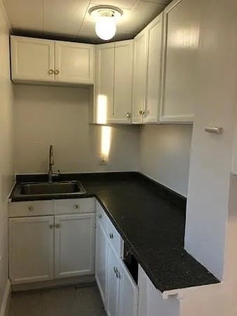 32 Wamesit Street, Unit 2 Lowell, MA 01852 - Photo 7 of 9 a kitchen with granite countertop a sink and white cabinets