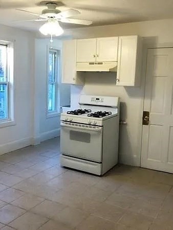 32 Wamesit Street, Unit 2 Lowell, MA 01852 - Photo 8 of 9 a kitchen with stainless steel appliances granite countertop a stove a sink and white cabinets