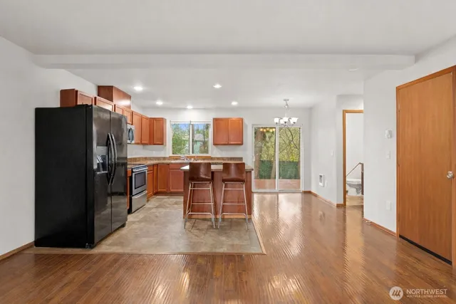 a kitchen with stainless steel appliances refrigerator wooden floor dining table and chairs