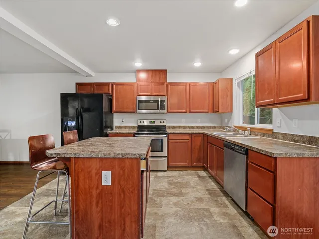 a kitchen with stainless steel appliances granite countertop wooden cabinets refrigerator and a stove top oven