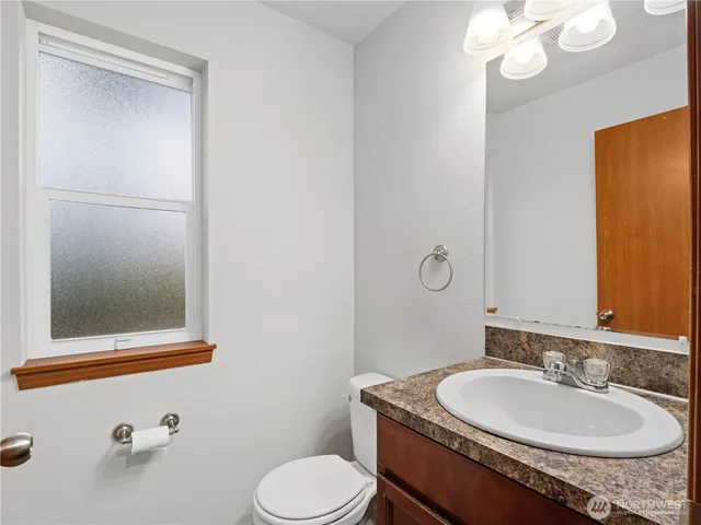 a bathroom with a granite countertop sink toilet and mirror