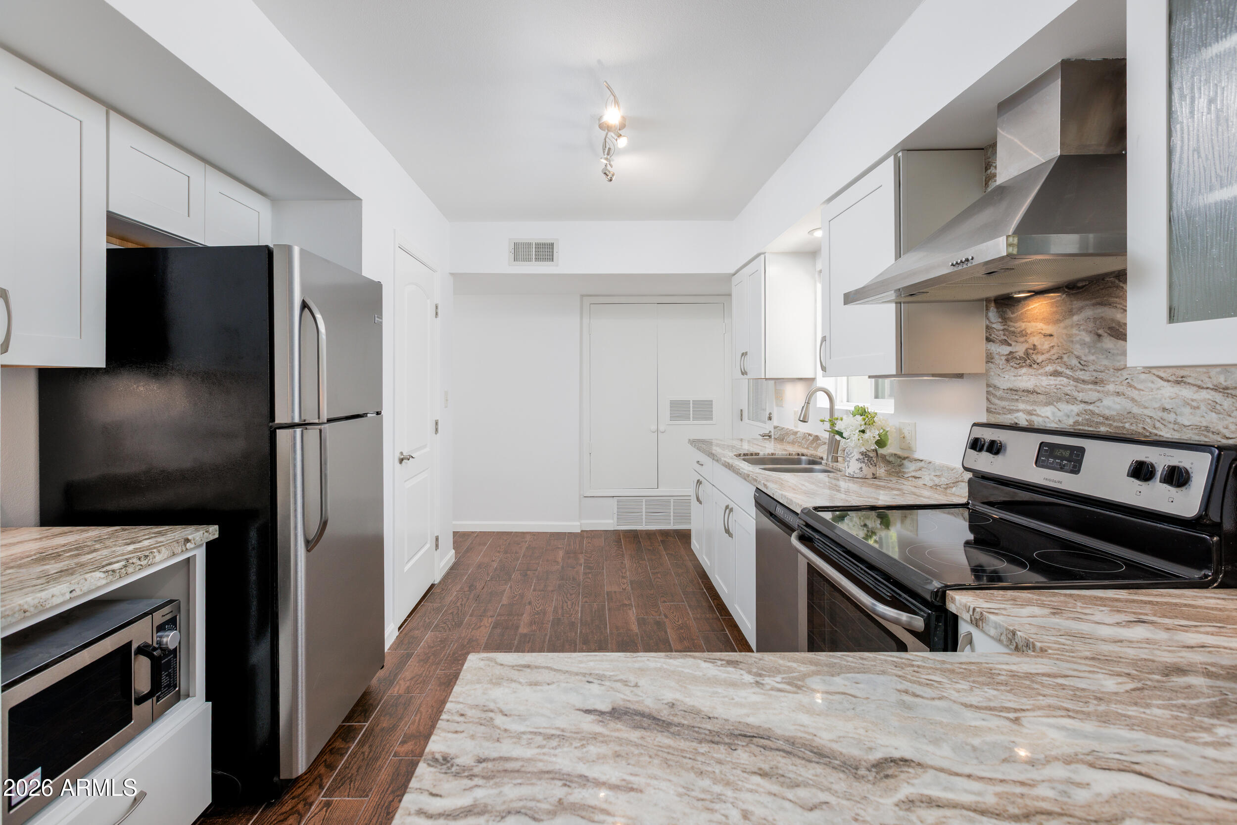 5550 North 12th Street, Unit 8 Phoenix, AZ 85014 - Photo 7 of 25 a kitchen with stainless steel appliances granite countertop a stove top oven a sink dishwasher a refrigerator and a oven with wooden floor