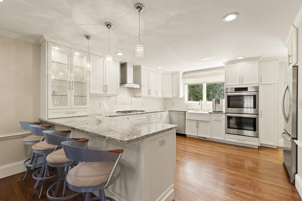 60 Amherst Road Newton, MA 02468 - Photo 3 of 25 a kitchen with stainless steel appliances granite countertop a stove a refrigerator a sink dishwasher a dining table and chairs with wooden floor